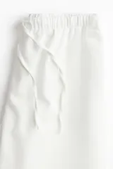 Pantalón de corte holgado color blanco, confeccionado en denim extrasuave. Modelo con cintura elástica, cordón para ajustar, bolsillos laterales discretos y piernas anchas.