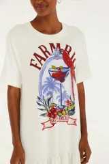 Vestido largo blanco con estampado de cóctel, palmeras y un loro. Tiene escote recto y corte fluido.