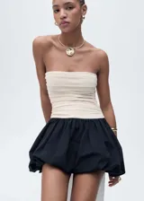 Vestido corto evasé, palabra de honor, con diseño drapeado y combinado en color crudo y negro. Falda globo con cierre de cremallera invisible lateral.
