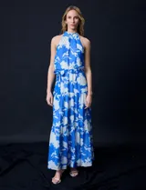 Vestido largo de gasa con estampado floral en tonos celeste y blanco. Tiene escote halter, cintura elastizada con lazo de ajuste, abertura en la espalda con botones y forro interno.