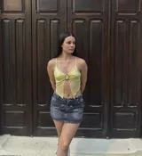 Top amarillo pálido con breteles finos, escote en V y abertura en el abdomen con detalle de hebilla metálica.