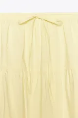 Falda larga color amarillo pastel, de tiro medio con cintura elástica ajustable con lazada y bajo acabado en paneles.