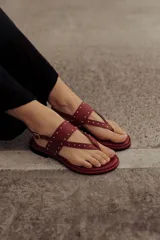 Sandalias marrones de cuero con tiras, microtachas doradas y hebilla lateral.