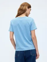 Remera de manga corta color blanco roto (off white) con cuello redondo y un pequeño bordado de un oso en el pecho.