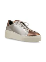 Sneaker de cuero graneado color plateado con detalles en color cobre en la puntera y el talón. Tiene suela elevada color hueso y cordones de algodón.