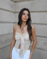 Top strapless color beige con textura de encaje y lazo frontal.