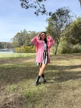 Camisa oversize de fibrana color rosa con botones rojos en forma de corazón y mangas largas con ajuste en los puños.