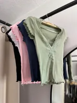 Remera corta de color verde claro con detalles de encaje en el escote y mangas cortas.