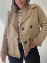 Chaqueta marrón con forro tipo corderito, doble botonadura y cuello con solapas.