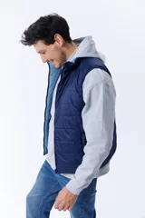 Chaleco acolchado azul marino con cierre frontal y cuello alto. Reversible, con interior en tono celeste. Sin mangas.
