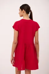 Vestido corto de lino color vino tinto, con escote en V y mangas cortas tipo musculosa. Presenta un corte holgado con volados en el ruedo.