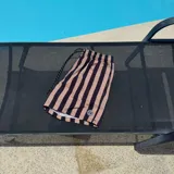 Short de baño negro con rayas verticales blancas, cintura elástica con cordón ajustable y logo de la marca en la pierna derecha.