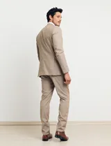 Traje de vestir color tostado, compuesto por saco con solapa de muesca, cierre de dos botones, bolsillos con solapa y pantalón de corte recto.