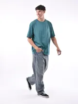 Remera gris de corte oversized, cuello redondo y mangas cortas. 