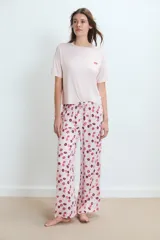 Pijama de dos piezas: remera rosa claro de manga corta con un pequeño bordado de labios en el pecho, y pantalón largo con estampado integral de labios en tonos rosados y bordó.