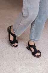 Sandalia plana de color tostado confeccionada en una combinación de neopreno y cuero. Posee un diseño de tira ancha con aberturas sobre el empeine, plantilla acolchada y suela de goma con costuras a la vista.