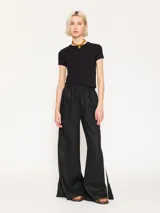 Pantalón negro de lino, de calce wide leg y tiro medio. Su diseño incluye cintura elastizada para mayor comodidad, bolsillos delanteros y cinta espiga en laterales.