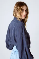 Camisa blanca de lino y lyocell, de corte clásico, con cuello camisero y mangas largas abullonadas con puños abotonados.