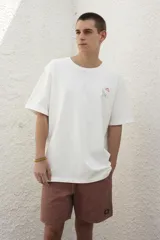 Remera blanca de algodón con estampado en la espalda con la frase "Follow the Waves" y dibujos de conchas marinas en color celeste.