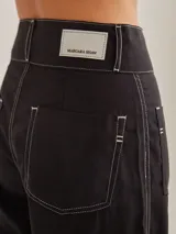 Pantalón negro de tiro medio alto, corte palazzo, con bolsillos delanteros y traseros.