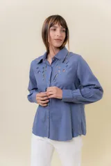 Camisa de manga larga color bordó oscuro, con cuello clásico y bordado calado decorativo en el área del pecho y hombros. Presenta un calce relajado y cierre frontal de botones.