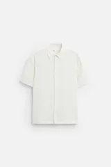 Camisa color blanco hueso de corte recto, con cuello solapa, manga corta y cierre frontal con botones.