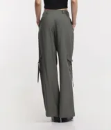 Pantalón cargo de viscosa color verde oliva, corte sastrero, con bolsillos laterales, cierre con botón y cremallera, y ajustadores en los tobillos.