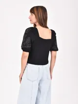 Remera negra de mangas cortas abullonadas con bordado floral en las mangas y escote cuadrado.