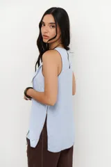 Musculosa color crudo con cuello redondo y ribete marrón en cuello, sisas y ruedo. Diseño cruzado en el frente y aberturas laterales.