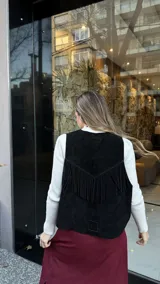 Chaleco negro de cuero descarne con terminación en picos y tachas metálicas.