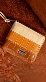 Billetera corta con cierre perimetral, confeccionada en símil cuero con textura croco. Interior con visor, tarjetero, división para billetes y bolsillo monedero con tapa y broche.