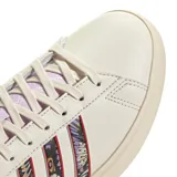 Championes Adidas Grand Court 2.0 color crema con las tres tiras laterales estampadas con diseño de mariposas y flores. Detalles en color lila en el talón, lengüeta y cordones.