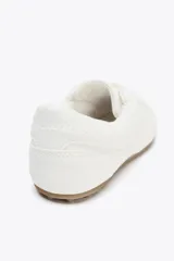 Zapato deportivo tipo blucher color blanco con suela marrón.