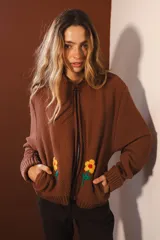 Bomber negra con rayas verticales blancas y flores rojas bordadas. Tiene cierre frontal y bolsillos.