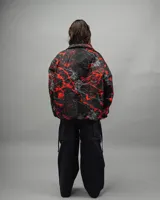 Campera reversible negra con estampado abstracto en rojo y blanco, de corte amplio y cuello camisero.