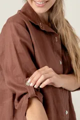 Vestido camisero negro de lino con botones, mangas 3/4 con trabilla y bolsillo de parche en el pecho con bordado de letras. Tiene aberturas laterales en el ruedo y costuras a contratono en color crudo.