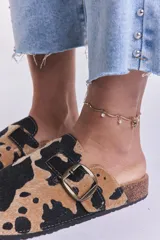 Zuecos con estampado de vaca en tonos camel y negro, con hebilla metálica ajustable y plantilla anatómica.