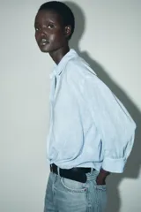 Camisa blanca de cuello solapa y manga larga con puños. Tiene un nudo en la parte delantera y cierre frontal con botones.
