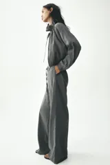 Pantalón palazzo color gris topo de tejido fluido, con cintura elástica ajustable con cordones y bolsillos laterales.