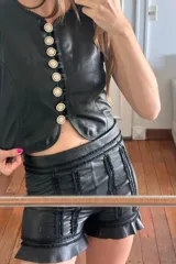 Short de cuero ovino negro con bordados y volados en el ruedo.