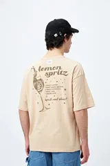 Remera blanca de corte holgado con mangas cortas y cuello redondo. Estampado pequeño en el frente con la frase "Spritz and Shine" en verde.