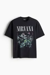 Remera negra de algodón con estampado vintage de la banda Nirvana y el nombre de la banda en letras blancas.