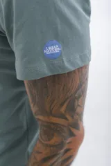 Remera de manga corta color verde azulado con cuello redondo y estampado frontal con el texto "UH3" en blanco.