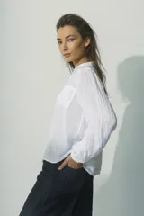 Camisa de manga larga con cuello camisero y cierre frontal con botones. Diseño a rayas verticales color beige y blanco, con dos bolsillos de parche en el pecho.