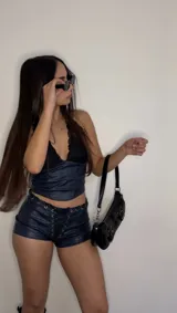 Conjunto de top y shorts de cuero sintético color azul marino. El top es de corte halter con detalles de encaje negro en el escote. Los shorts son de tiro alto con cordones cruzados en la parte delantera.