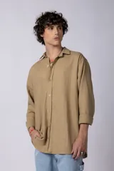 Camisa color arena de lino, manga larga, con cuello clásico y corte holgado.