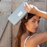 Billetera larga negra con cierre perimetral y placa metálica con logo. Posee múltiples compartimentos internos para tarjetas y documentos, además de un bolsillo con cierre interior. Incluye correa de mano desmontable.