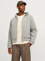Campera gris melange con capucha, cierre frontal con cremallera, bolsillos laterales y puños elásticos.