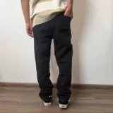 Jean de hombre color negro con efecto lavado, de corte mom fit, con cintura elástica y puños ajustados en los tobillos.