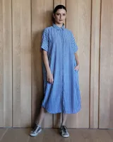 Vestido túnica celeste de lino con rayas verticales blancas, corte recto, cuello camisero y mangas cortas.